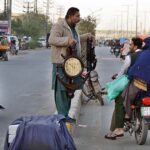 A vendor displaying wall clocks to customers on motorcycle in Provincial Capital