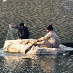 Fisherman busy in fishing on the handmade boat at water canal