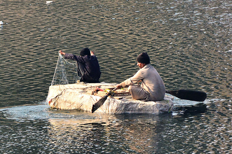 Fisherman busy in fishing on the handmade boat at water canal