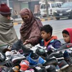 A family buys old shoes from a roadside vendor to protect against the harsh cold weather.