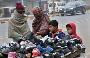 A family buys old shoes from a roadside vendor to protect against the harsh cold weather. 