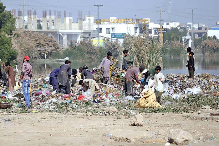 Gypsy youngsters searching and collecting recycle items from heap of garbage near Qasim Chowk.