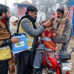 Polio worker team administrating polio drops to children at University road.