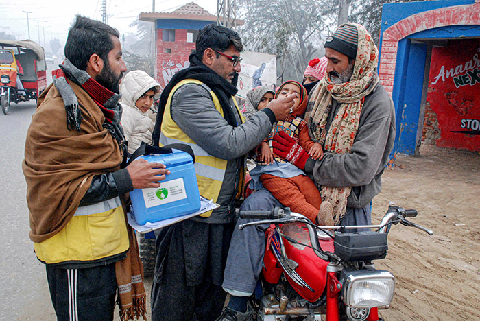Polio worker team administrating polio drops to children at University road.