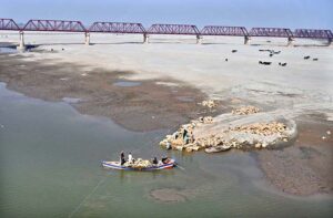 Workers of Irrigation Department shifting stones through boat to the other side of the River.