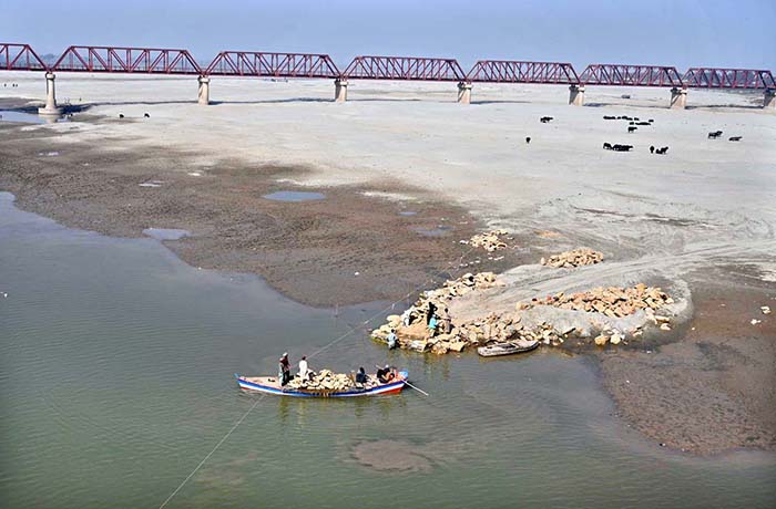 Workers of Irrigation Department shifting stones through boat to the other side of the River.