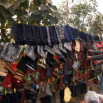 A vendor is busy in displaying and selling Warm hats, scarves and gloves at his roadside setup