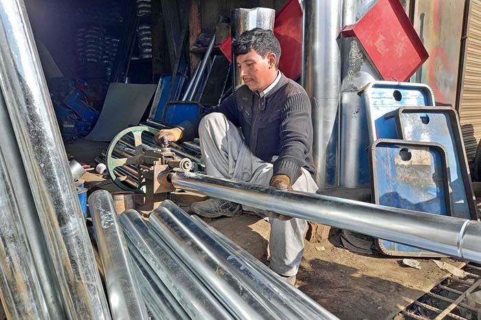 A skilled person making steel pipe and other items for the firewood stove at his work place as per increased demand in winter session.