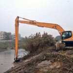 Irrigation department worker cleaning a canal with the help of caterpillar during canal cleaning campaign