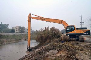 Irrigation department worker cleaning a canal with the help of caterpillar during canal cleaning campaign