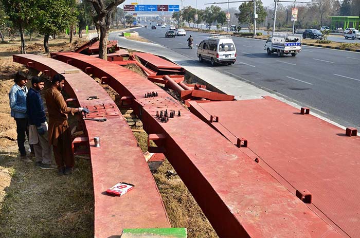 Workers busy in joining pedestrian bridge to be installed at Srinagar Highway in Federal Capital.