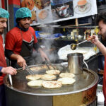 Vendors preparing traditional bread (Pratha) for customers at his roadside setup in the city