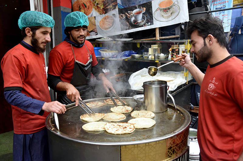 Vendors preparing traditional bread (Pratha) for customers at his roadside setup in the city