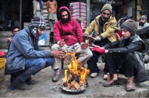 People are sitting around fire during cold weather in the city.