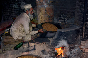 A vendor roasting grams for the customers at his workplace.