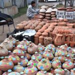 A vendor arranging and displaying the different kinds of clay pots to attract the customers at roadside setup