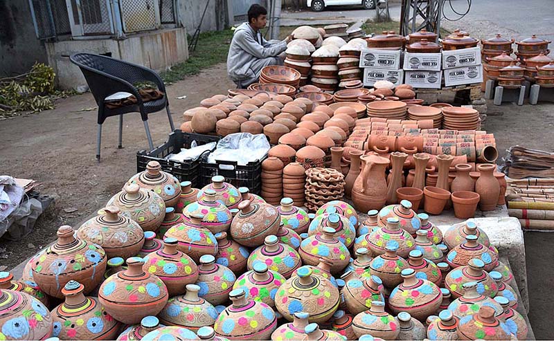 A vendor arranging and displaying the different kinds of clay pots to attract the customers at roadside setup