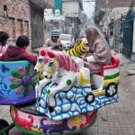 Children enjoy swings in a street.