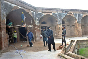 Labourers busy in restoration work on the wall of historical Tomb of Noor Jahan.