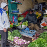 A vendor is selling vegetables to the customer.