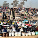 People busy in selecting and purchasing old shoes from vendor along expressway