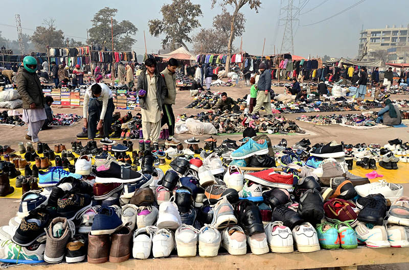 People busy in selecting and purchasing old shoes from vendor along expressway