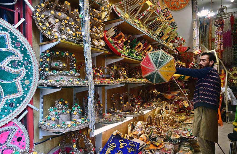 A shopkeeper arranging and displaying “Mehndi” related items to attract the customers at his shop in a local market