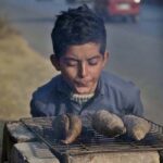 A boy roasts Sweat Potato at his roadside setup to earn for livelihood.