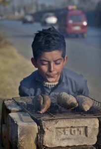A boy roasts Sweat Potato at his roadside setup to earn for livelihood.