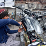 A young skilled worker is busy in Lamination work on the motorcycle.