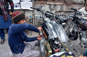 A young skilled worker is busy in Lamination work on the motorcycle. 
