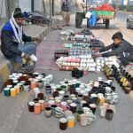 Vendor displaying tea cups to attract customers at roadside setup.