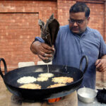 A vendor busy in preparing traditional food item (Jalebi) at his roadside setup