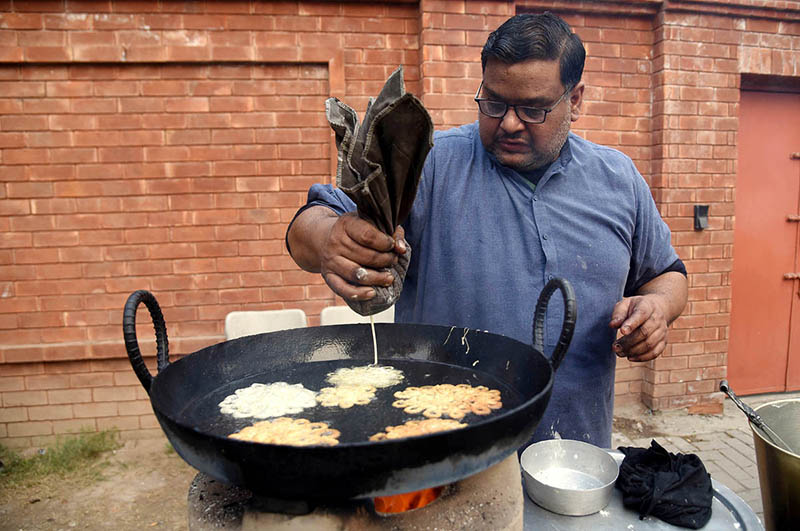 A vendor busy in preparing traditional food item (Jalebi) at his roadside setup