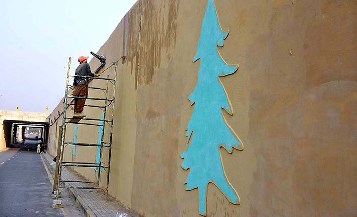 Worker busy paint on wall of Aabpara Underpass in the Federal Capital.