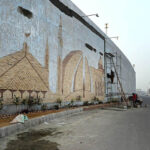Laborers busy in construction work to enhance the beauty of the city on the wall of a flyover at Rawal Dam Chowk in the Federal Capital