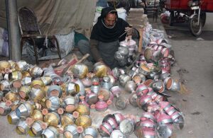 A vendor busy in preparing traditional smoking instrument (Huqqa) top Chilam at his workplace