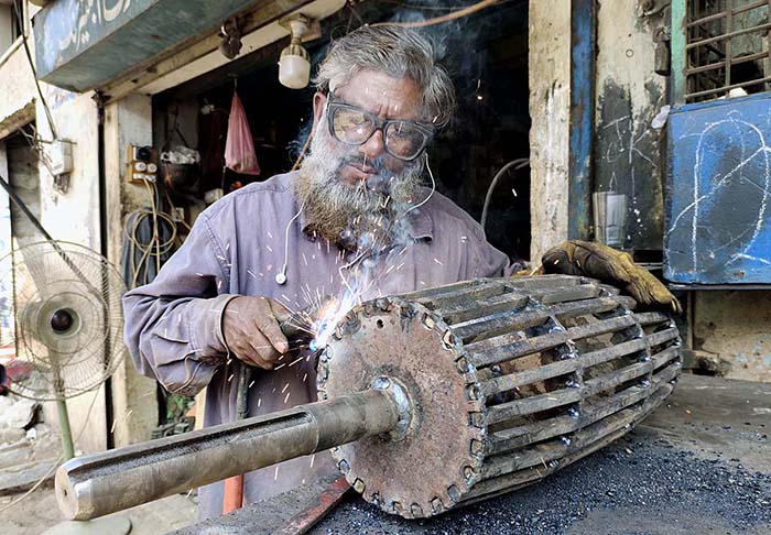 An elderly worker busy in welding work at his workplace.