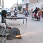 Laborers cutting iron plate at his workplace in a street.
