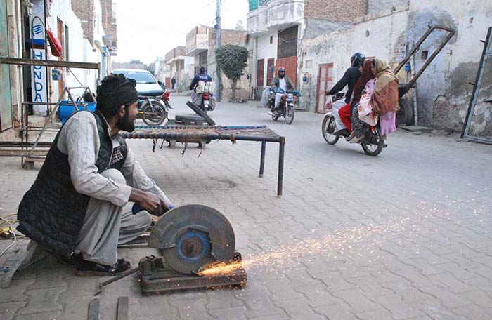 Laborers cutting iron plate at his workplace in a street.