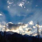 An attractive view of sun rays peeping from the clouds during the sun set in city.