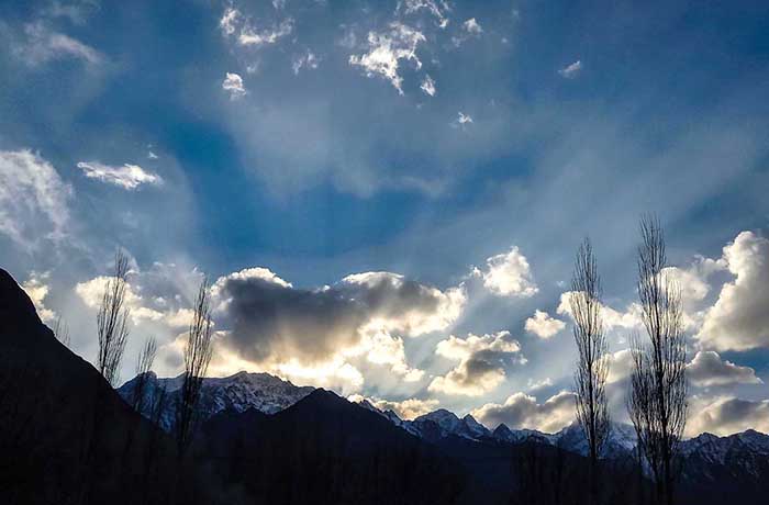 An attractive view of sun rays peeping from the clouds during the sun set in city.