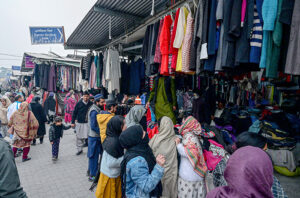  Customers selecting and purchasing old clothes displayed by the vendor at weekly Bazaar.