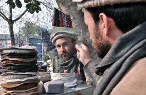 A person selecting and purchasing Chitrali Cap from roadside vendor in Federal Capital