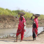 Villager women going back their homes carrying dirt on their heads