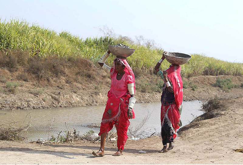 Villager women going back their homes carrying dirt on their heads