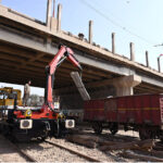 Railway worker unloading concrete Blocks from heavy Crain to lay on railway track near railway station