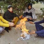 Vendors sitting around fire to keep them warm during cold weather in the city.