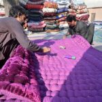 Worker busy in stitching cozy quilts for winter season at his workplace in the Federal Capital