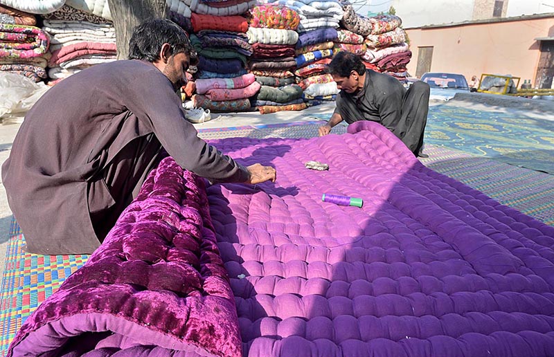 Worker busy in stitching cozy quilts for winter season at his workplace in the Federal Capital